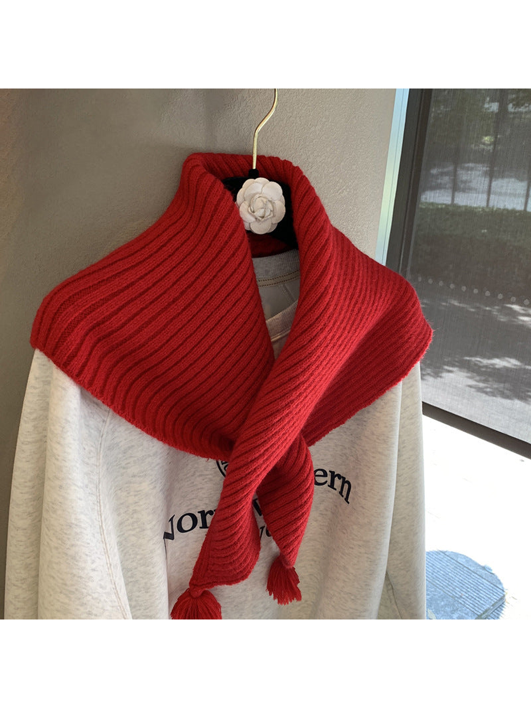 Close-up of the red scarf's ribbed texture and crossed pointed ends