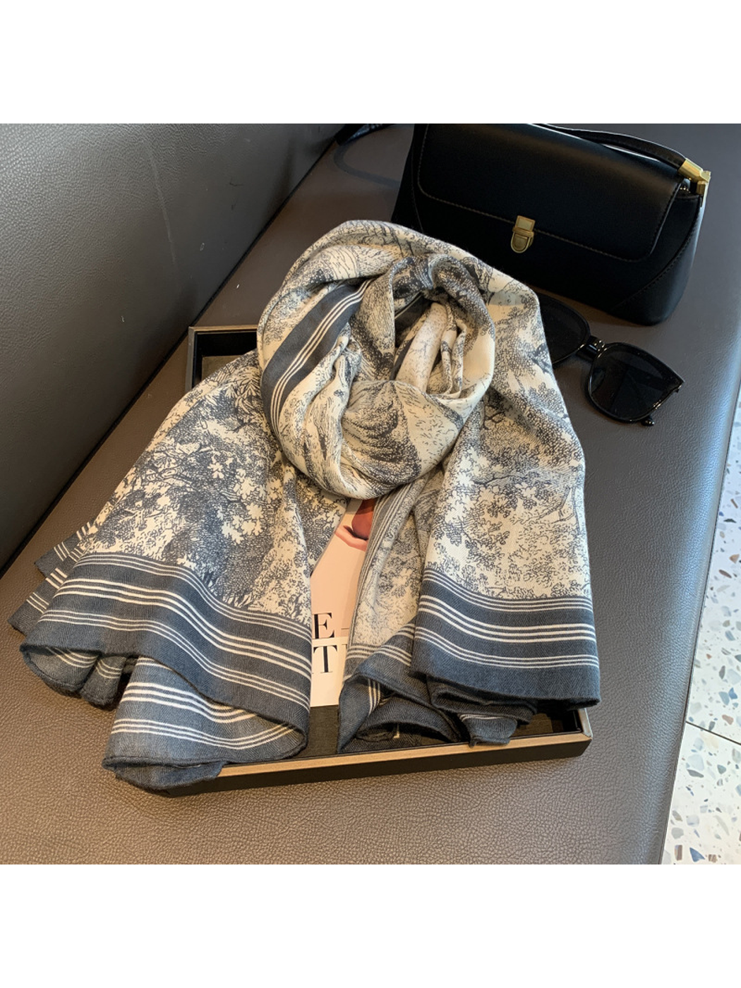 Ivory and gray-blue illustrated scarf arranged in a loose roll