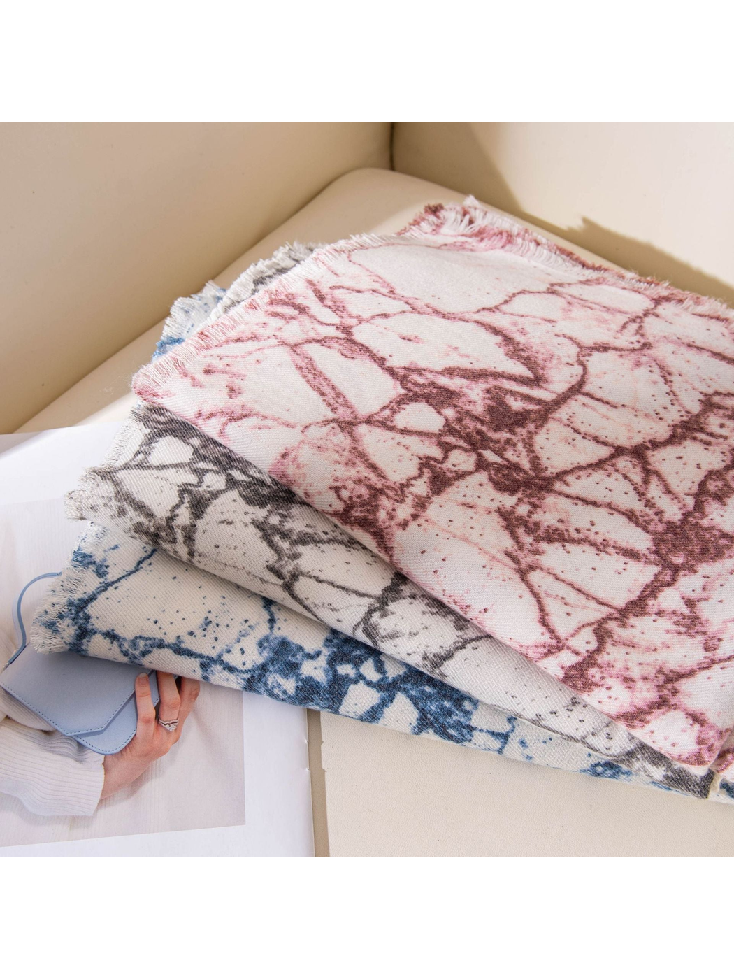 Burgundy, Black Gray and Blue abstract-print scarves stacked on a chair
