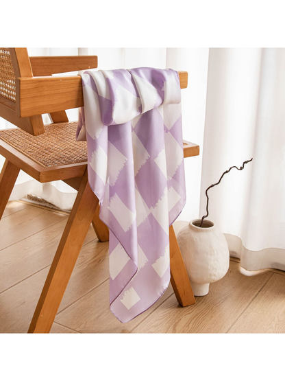 Light purple checkerboard scarf displayed beside a wooden chair and ceramic vase