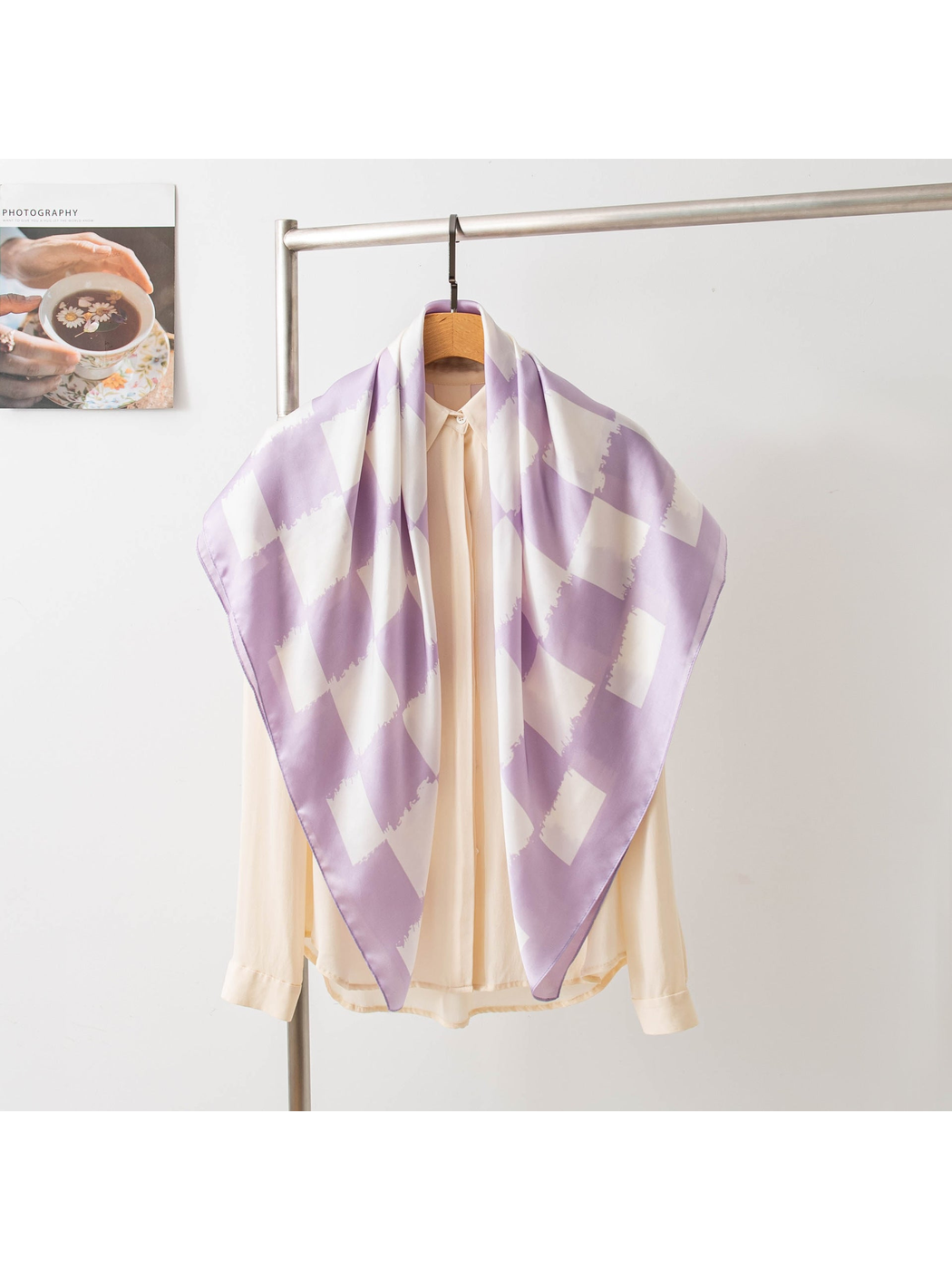 Light purple checkerboard scarf styled over a cream blouse on a hanger