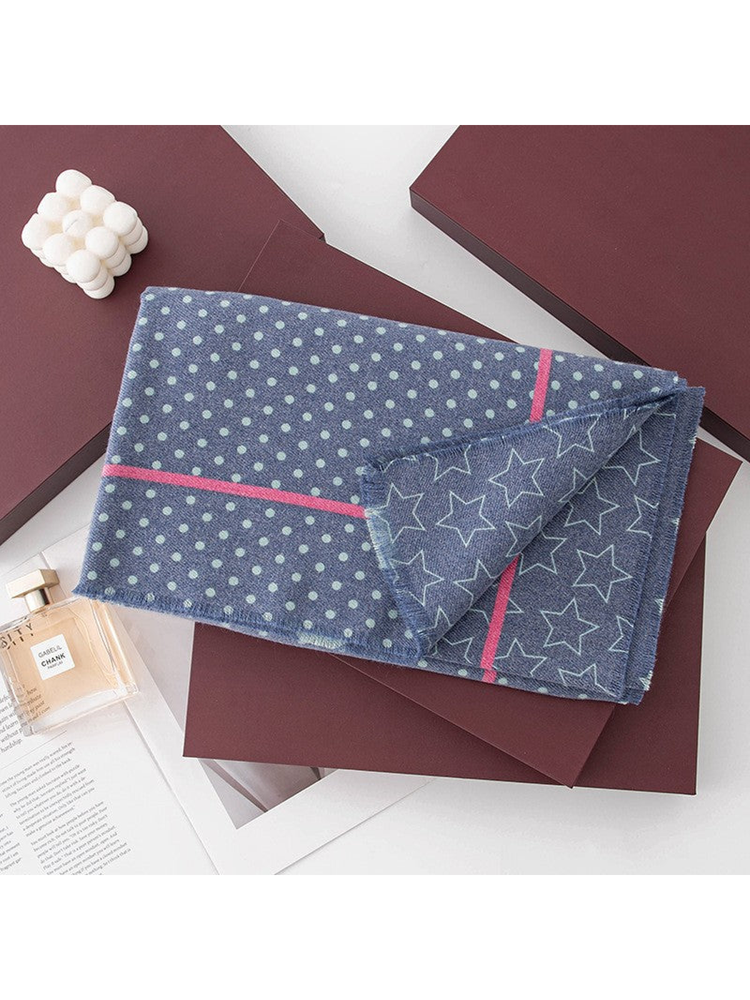 Folded navy patterned scarf styled with decorative tabletop props