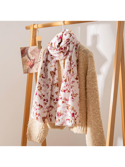 Ivory floral scarf styled over a cream knit sweater on a wooden rack