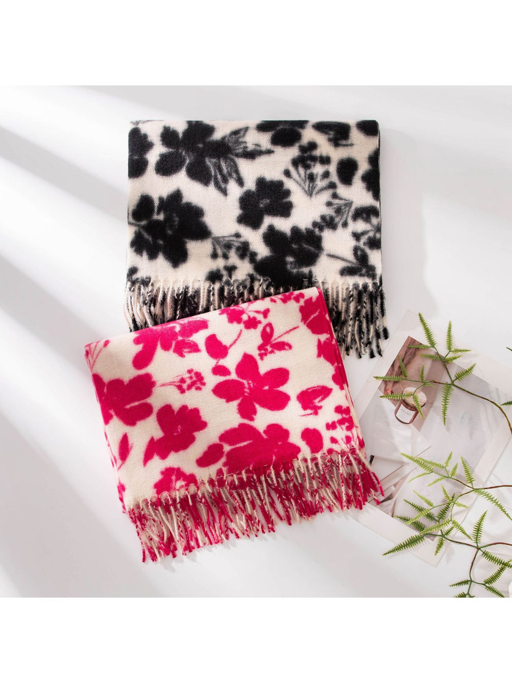 Pink and black floral scarves folded together with fringed ends