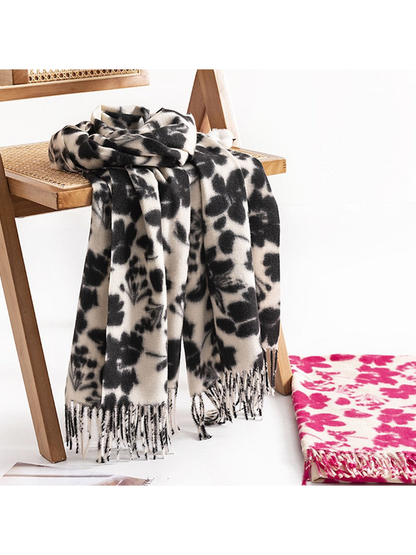 Black floral scarf draped over a chair beside a folded pink colorway