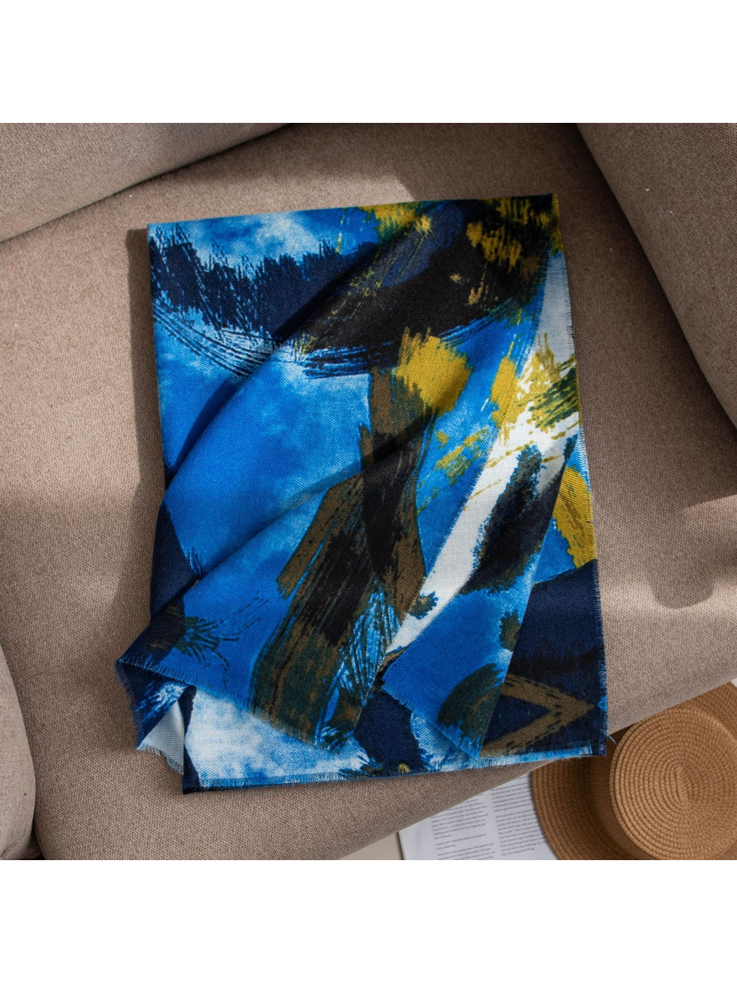 Blue abstract brushstroke scarf folded on a neutral sofa