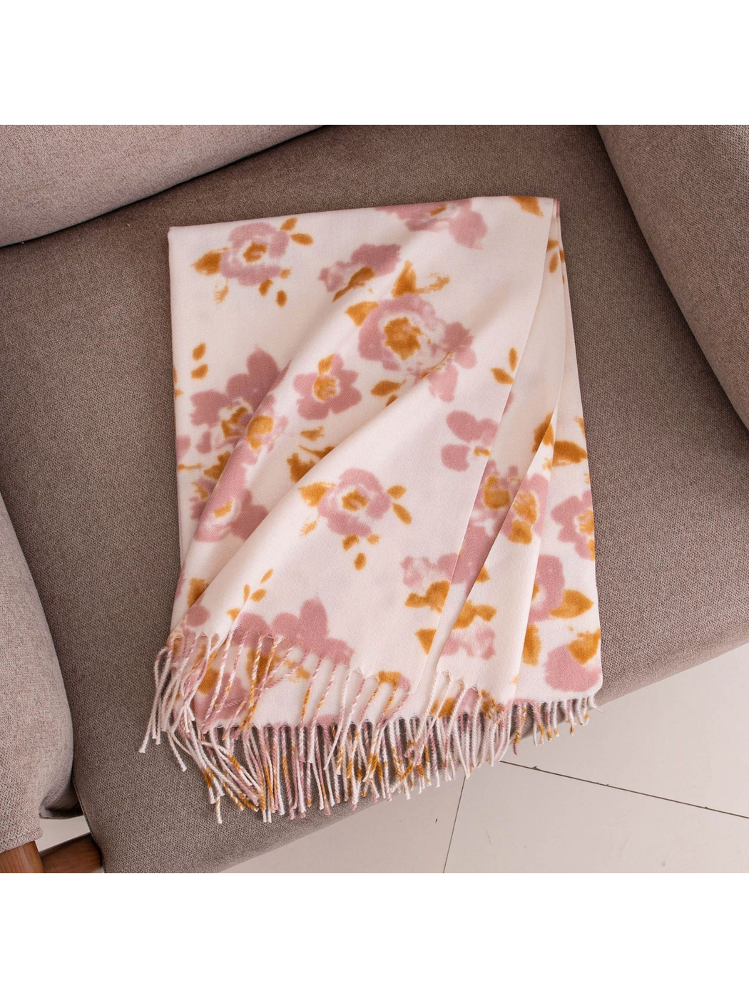 Folded pink and mustard floral scarf displayed on a chair