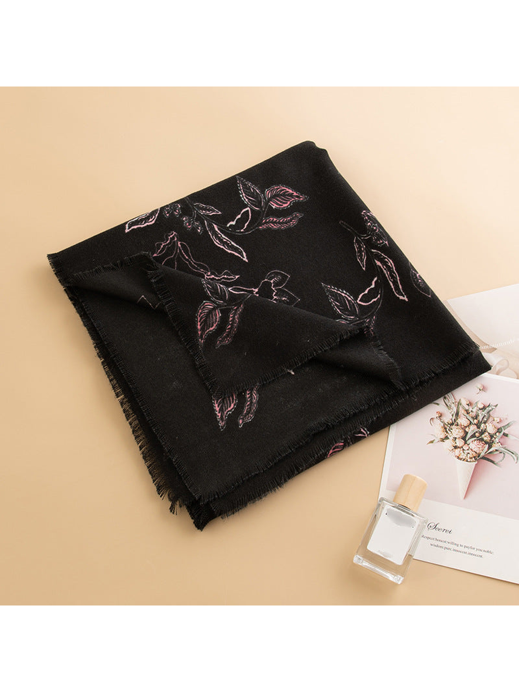 Folded black floral scarf styled on a beige tabletop