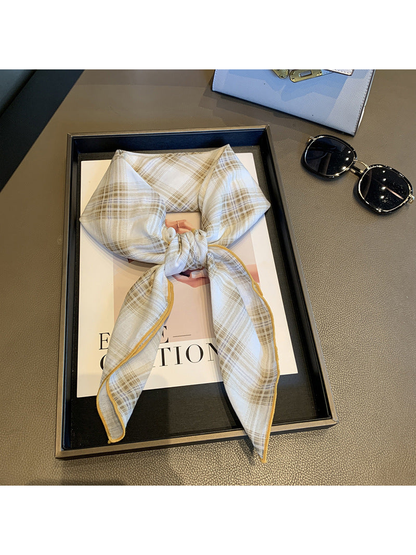 Ivory plaid scarf tied in a loose knot with golden edge stitching
