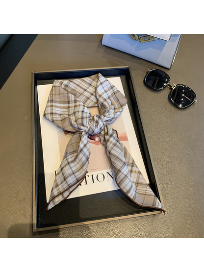 Khaki plaid scarf tied in a loose knot with brown edging