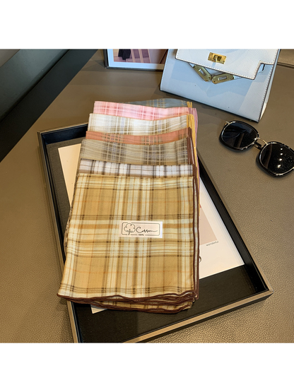 Multiple scarf colors folded and stacked to show their plaid patterns