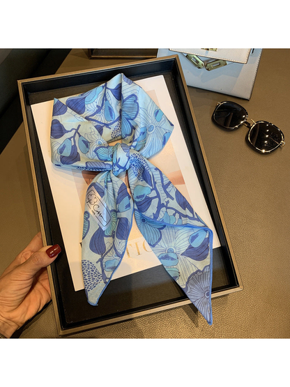 Blue floral square scarf arranged in a loose knot and held on a display tray