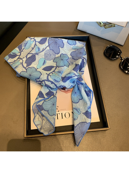 Blue floral square scarf loosely draped across a display tray