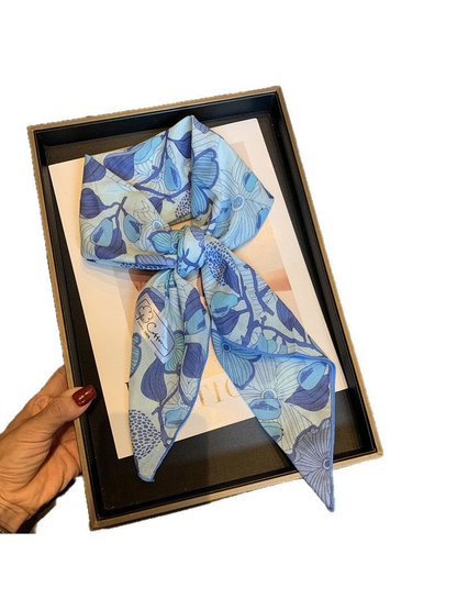 Blue floral square scarf tied in a loose knot against a white background