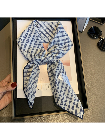Close view of the Blue White scarf's bow-and-flower pattern and finished edge