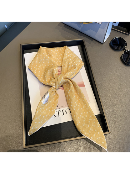 Yellow bow-and-flower square scarf tied in a loose knot