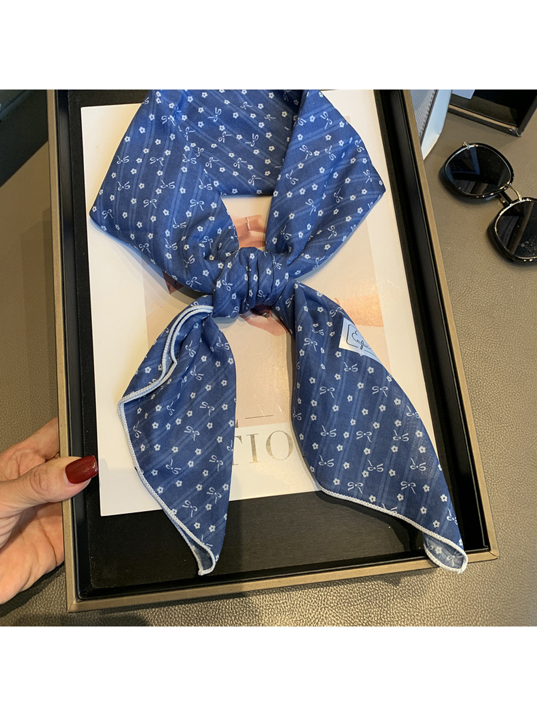Close view of the Navy scarf's lightly crinkled surface and bow-and-flower pattern