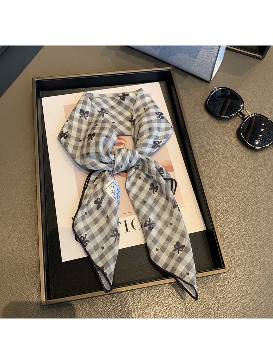 Gray gingham scarf with dark bow motifs, tied view