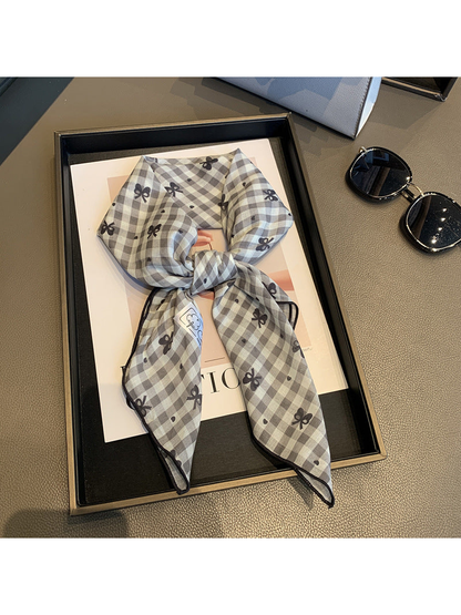 Gray gingham scarf with dark bow motifs, tied view