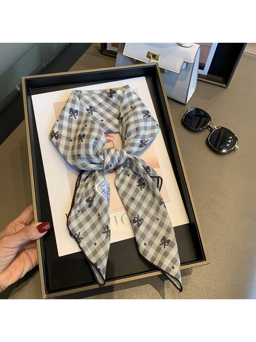 Gray gingham bow-print scarf tied and held in a display tray