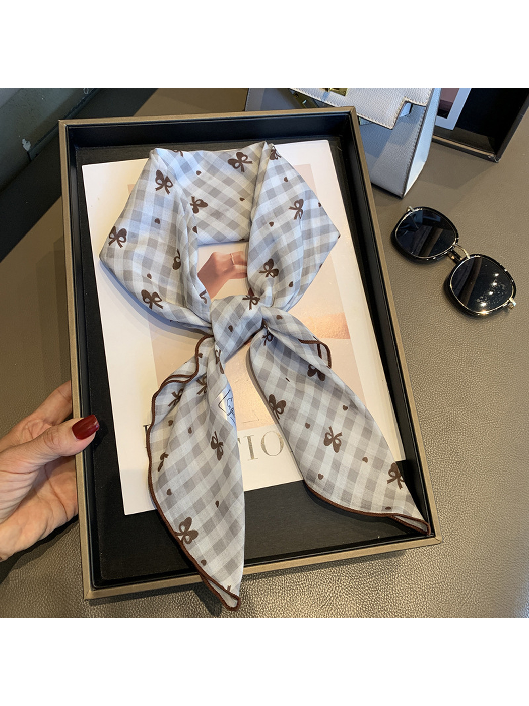 Beige gingham bow-print scarf tied and held in a display tray