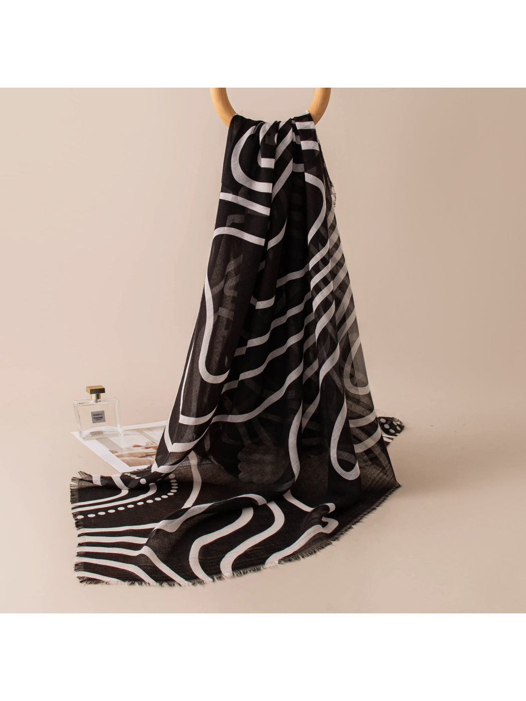 Black abstract-pattern scarf draped from a circular display stand