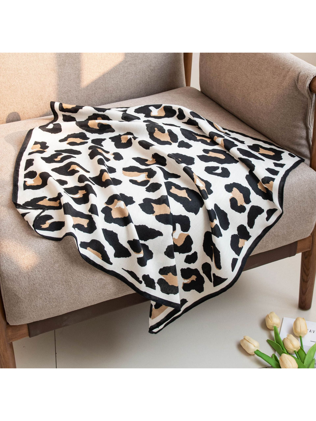 Black, tan and ivory cow print square scarf draped across a chair