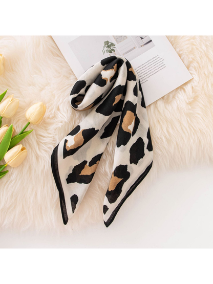Black, tan and ivory cow print square scarf arranged in a long drape