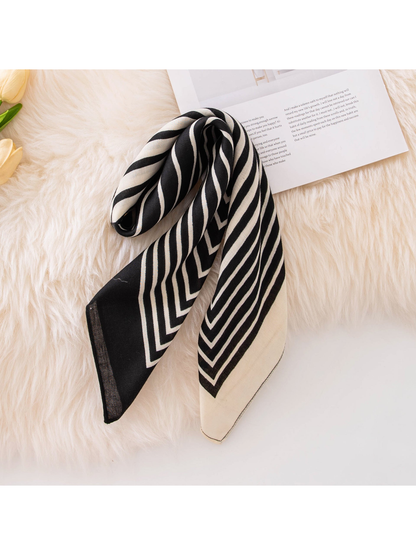 Black and ivory striped square scarf loosely folded on a light textured surface