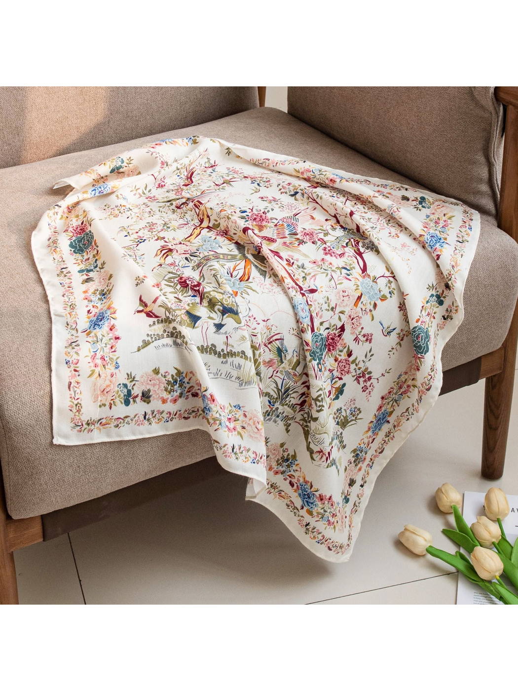 Ivory bird-and-floral square scarf spread across a neutral armchair
