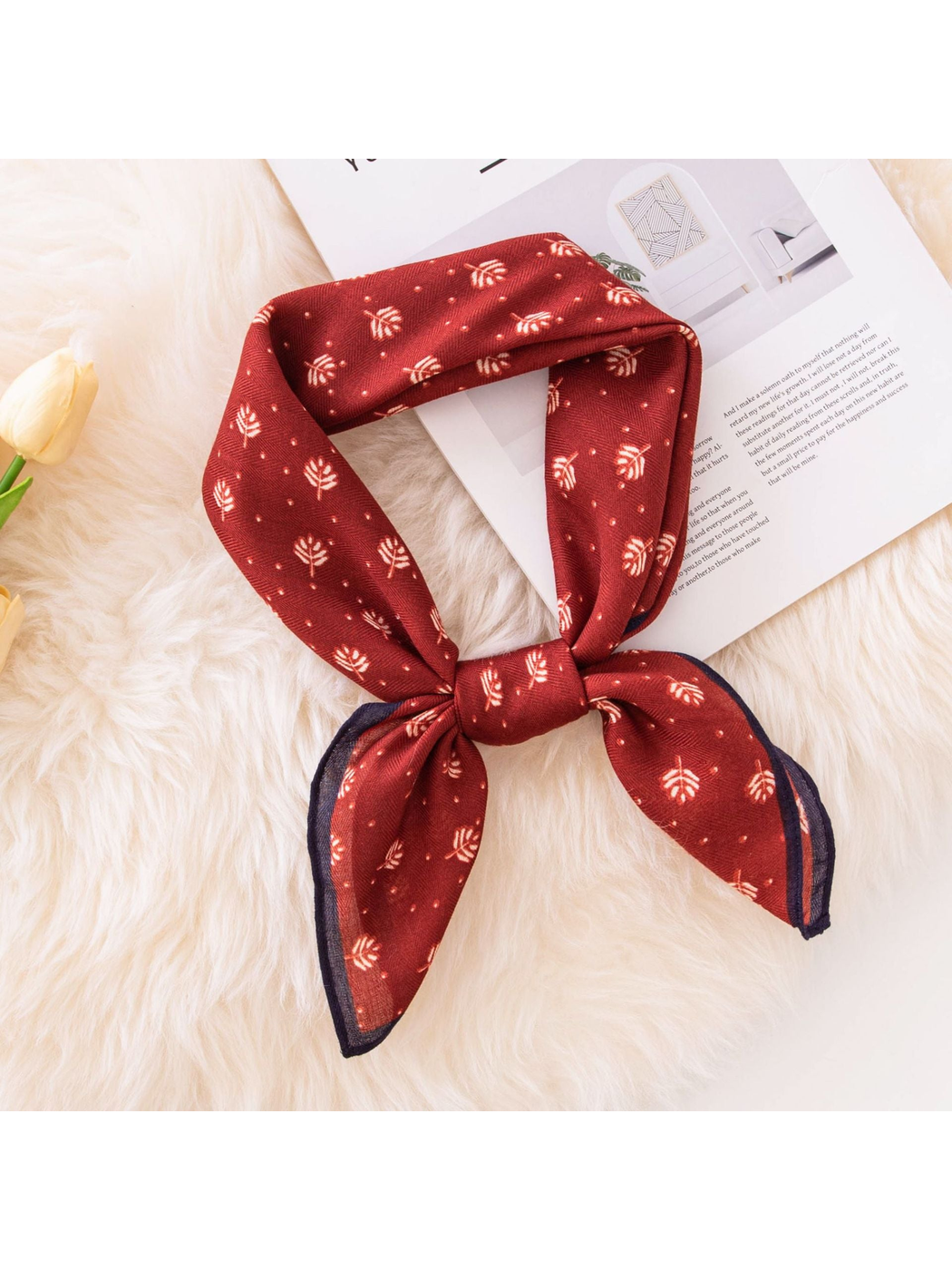 Red square scarf with cream leaf motifs tied in a loose knot