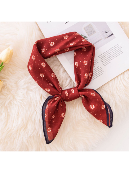 Red square scarf with cream leaf motifs tied in a loose knot