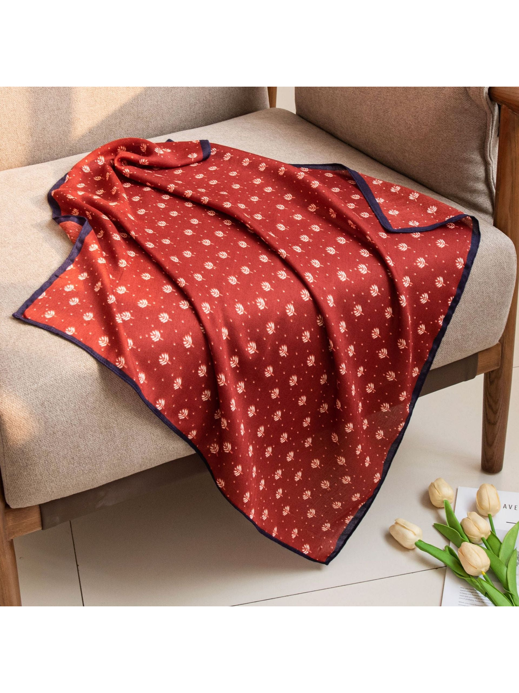 Red square scarf with cream leaf motifs draped across a chair