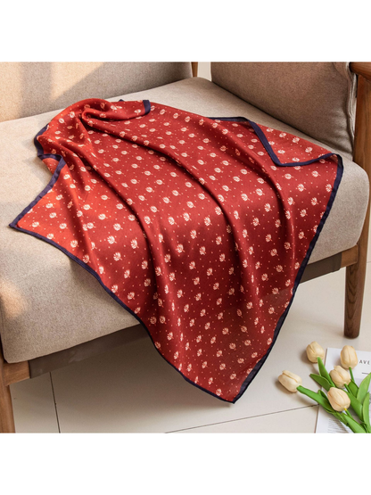 Red square scarf with cream leaf motifs draped across a chair