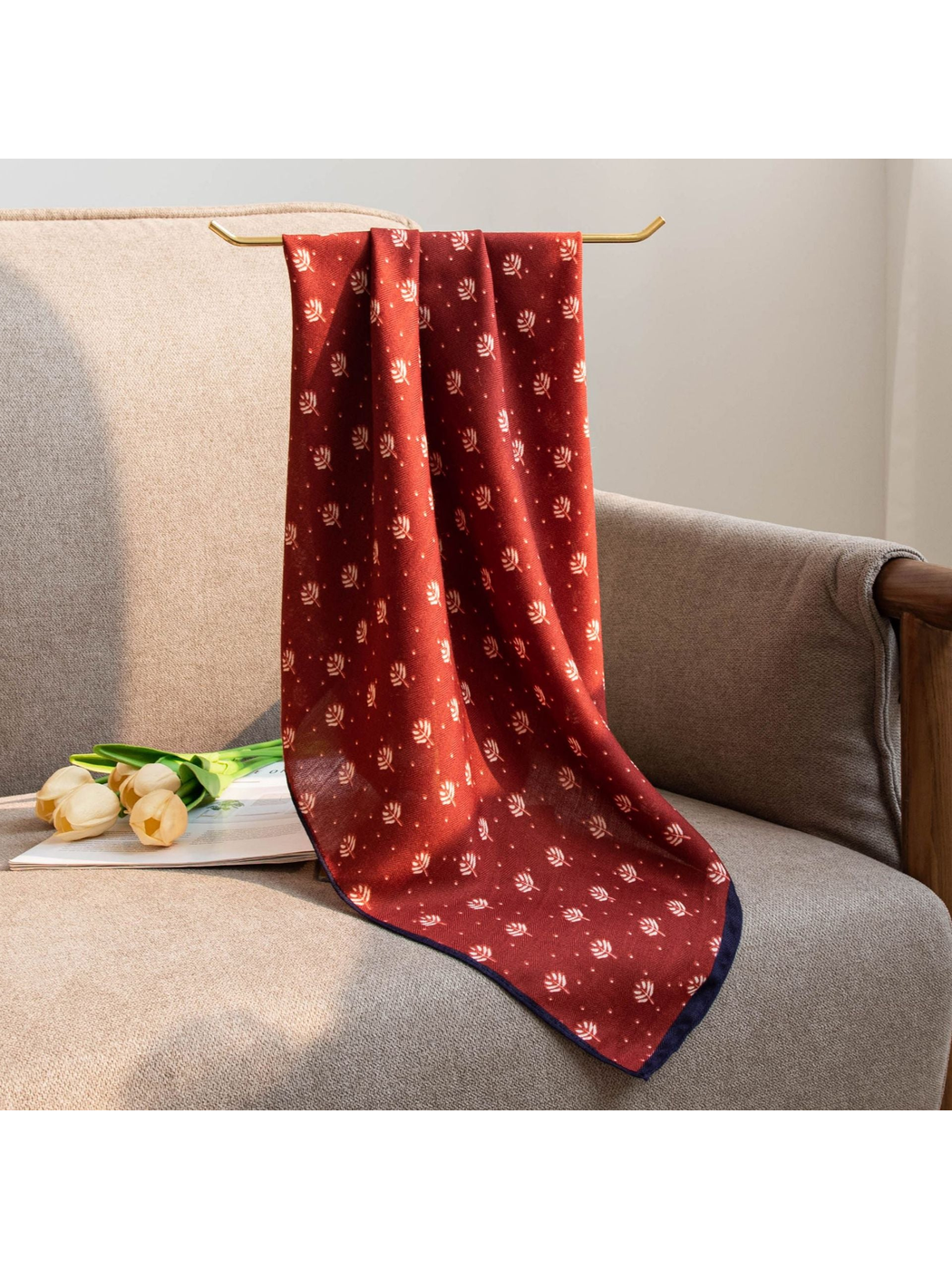 Red leaf-print square scarf hanging over a chair in natural light