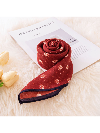 Rolled red square scarf with cream leaf motifs and navy border