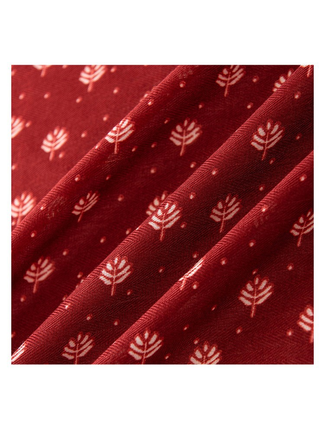 Close-up of cream leaf motifs and woven-look texture on red scarf
