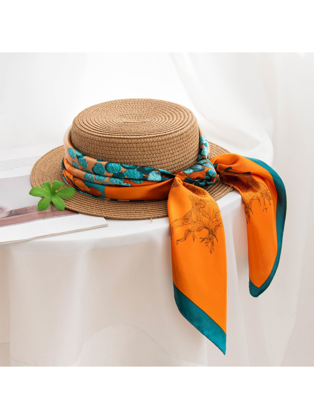 Orange and teal patterned scarf tied around a woven hat
