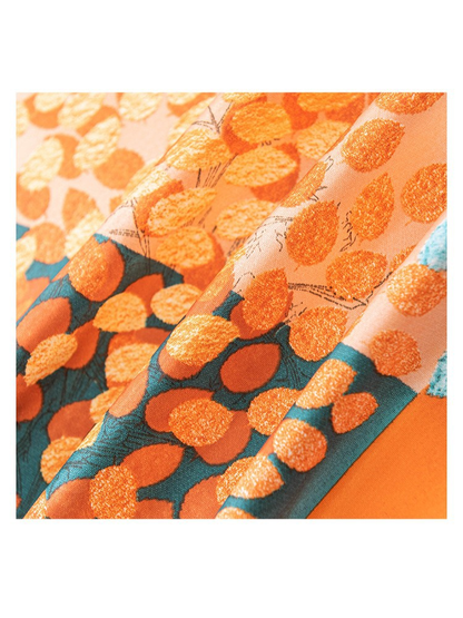 Close-up of the scarf's orange and teal leaf pattern and lustrous surface