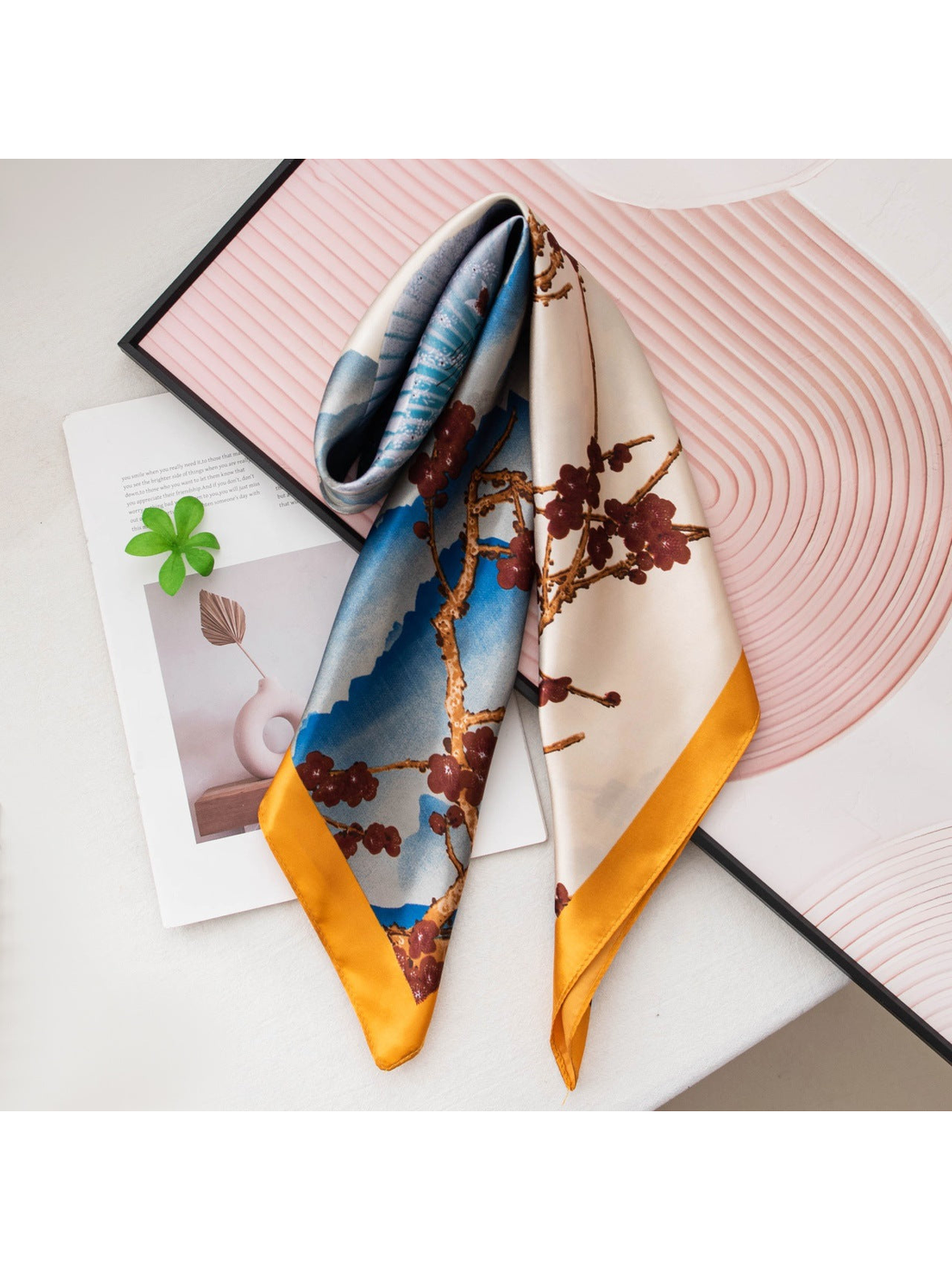 Blue and ivory square scarf folded on a pink decorative backdrop