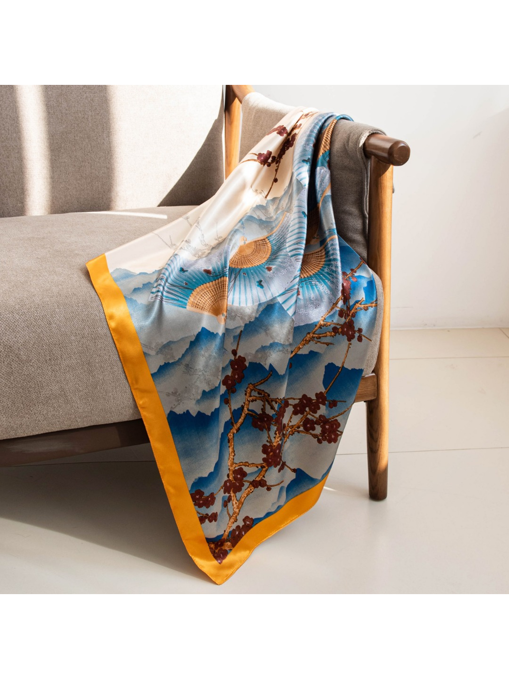 Blue and ivory square scarf draped over a neutral armchair in sunlight