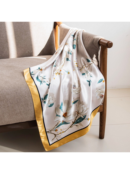 Floral square scarf draped over an armchair with its gold border visible