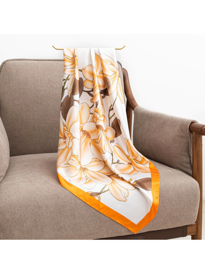 Orange-bordered floral square scarf draped over a gray armchair