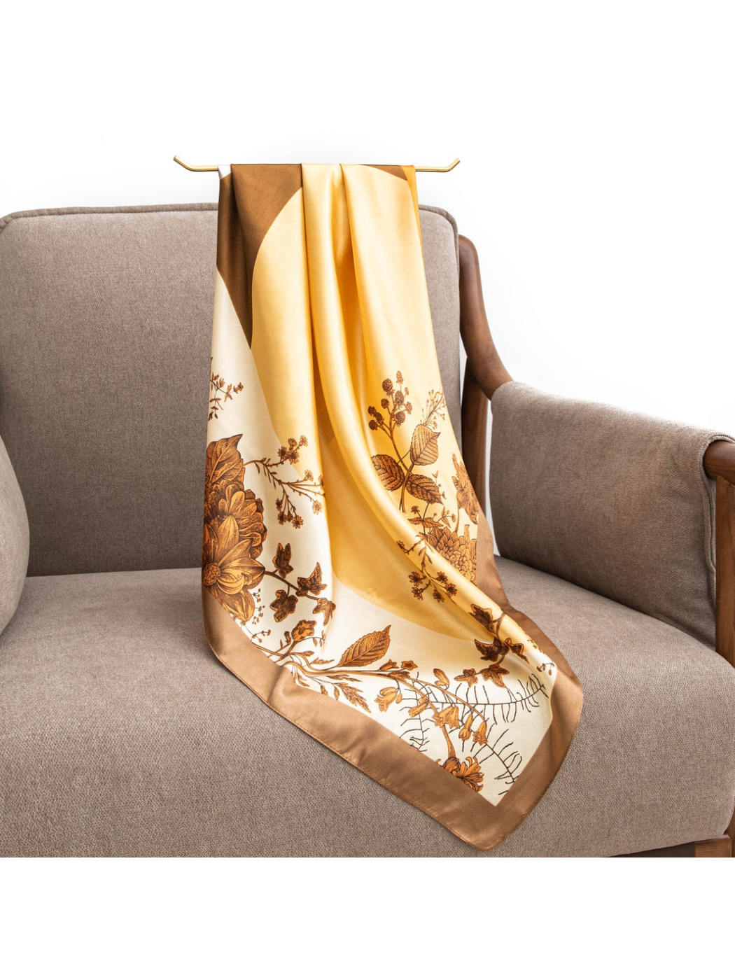 Orange, yellow, cream and brown botanical scarf draped over an armchair