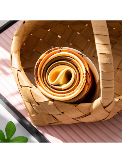 Close-up of the rolled orange, cream and brown scarf and its smooth finish