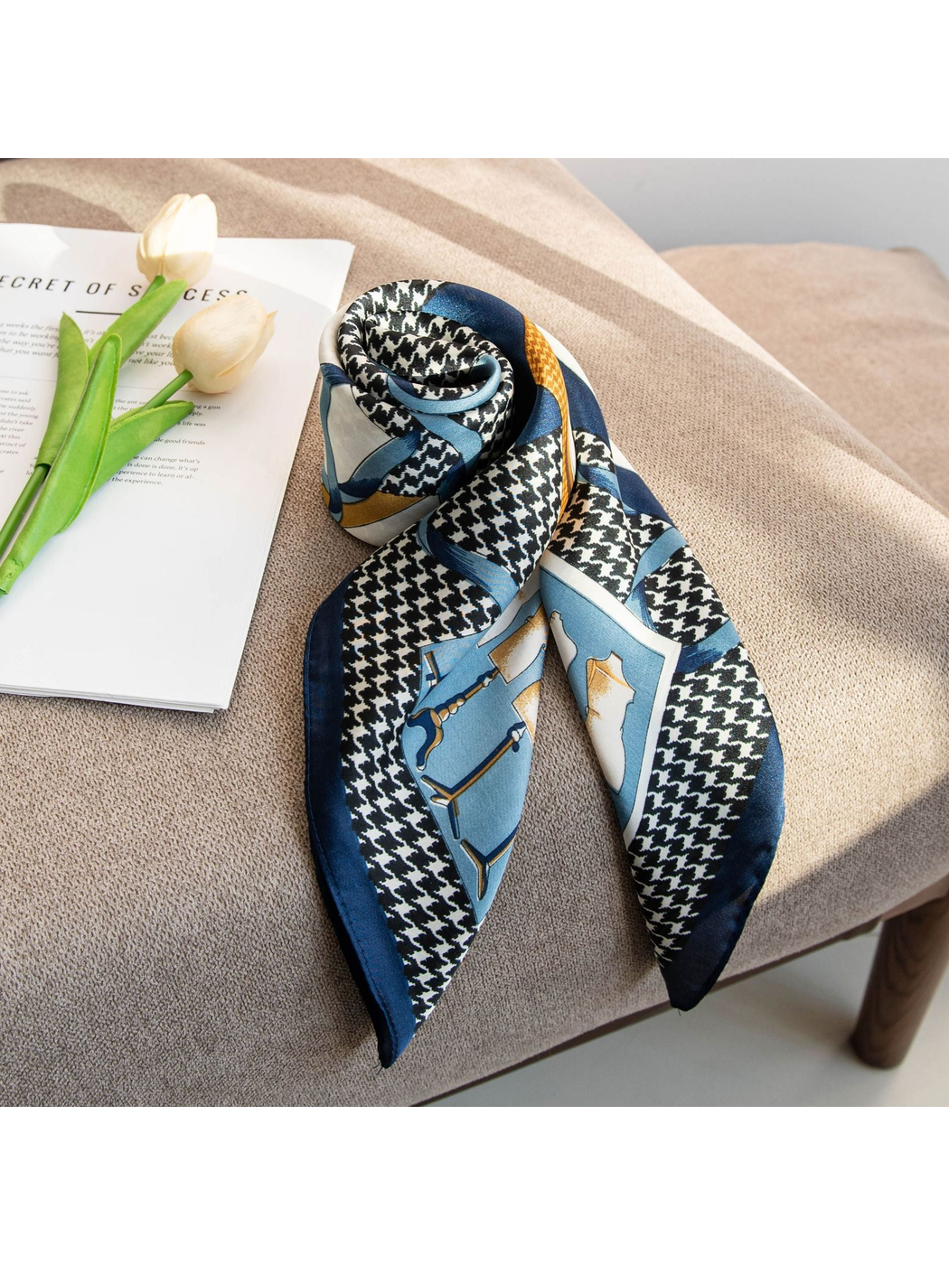 Patterned square scarf rolled and draped on a neutral chair