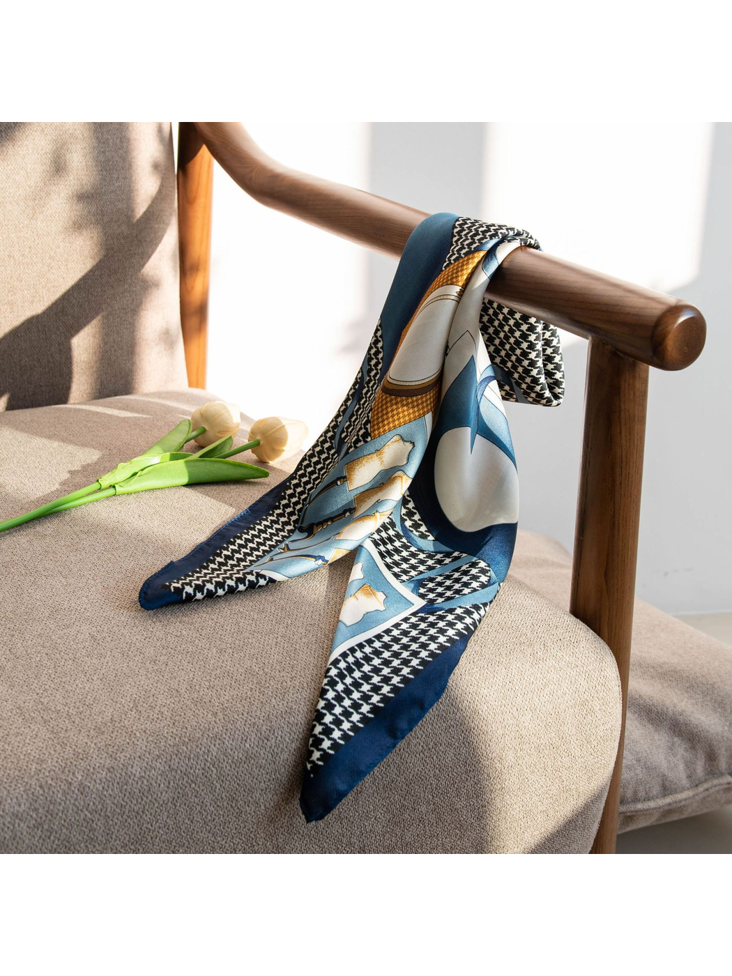 Patterned square scarf draped over a wooden chair arm in natural light