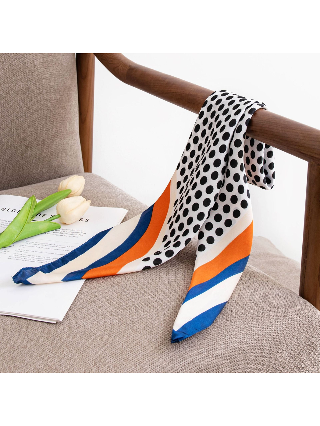 Polka-dot square scarf draped over a wooden chair arm beside tulips