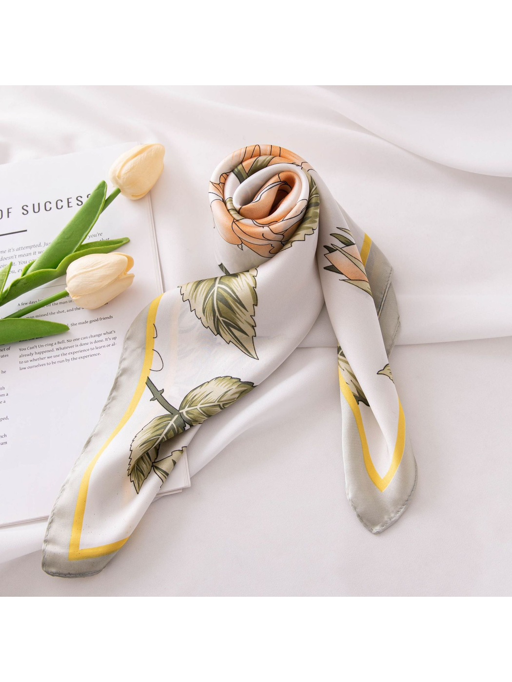 Peach rose floral scarf rolled and arranged on a white surface