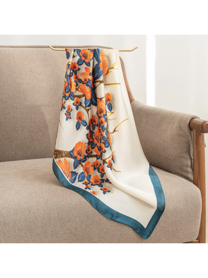 Cream square scarf with orange flowers, navy leaves and teal border draped over an armchair